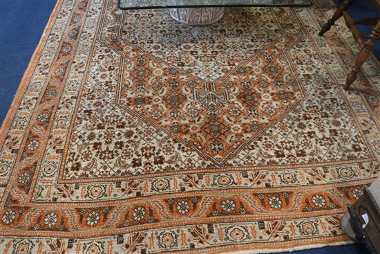 A Persian rug with heratic design on an orange and cream ground, 320cm x 210cm